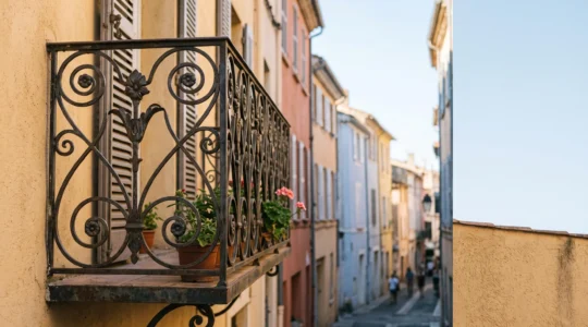 Grille de balcon en fer forgé finement ouvragée sur une façade ocre du centre historique de Perpignan